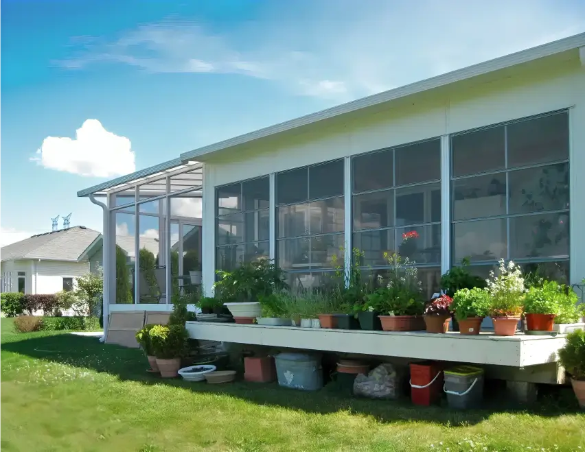 Sunspace Sunrooms Model 100 featuring large windows and a patio surrounded by a lush garden.