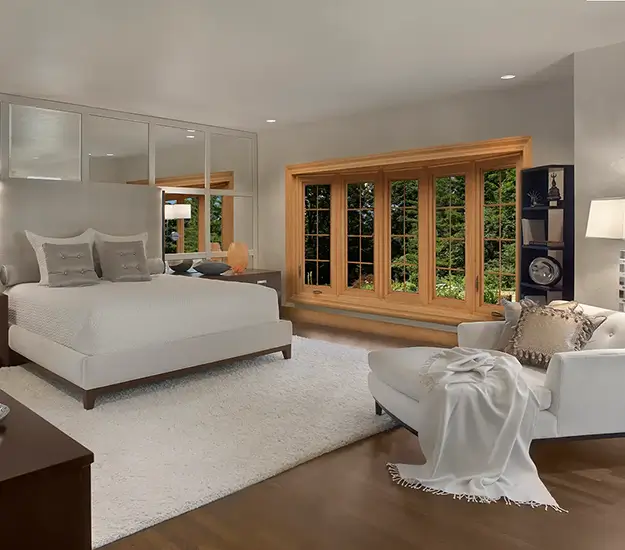 A well-furnished bedroom with a bed, a chair, a dresser, and a Window that brightens the room.