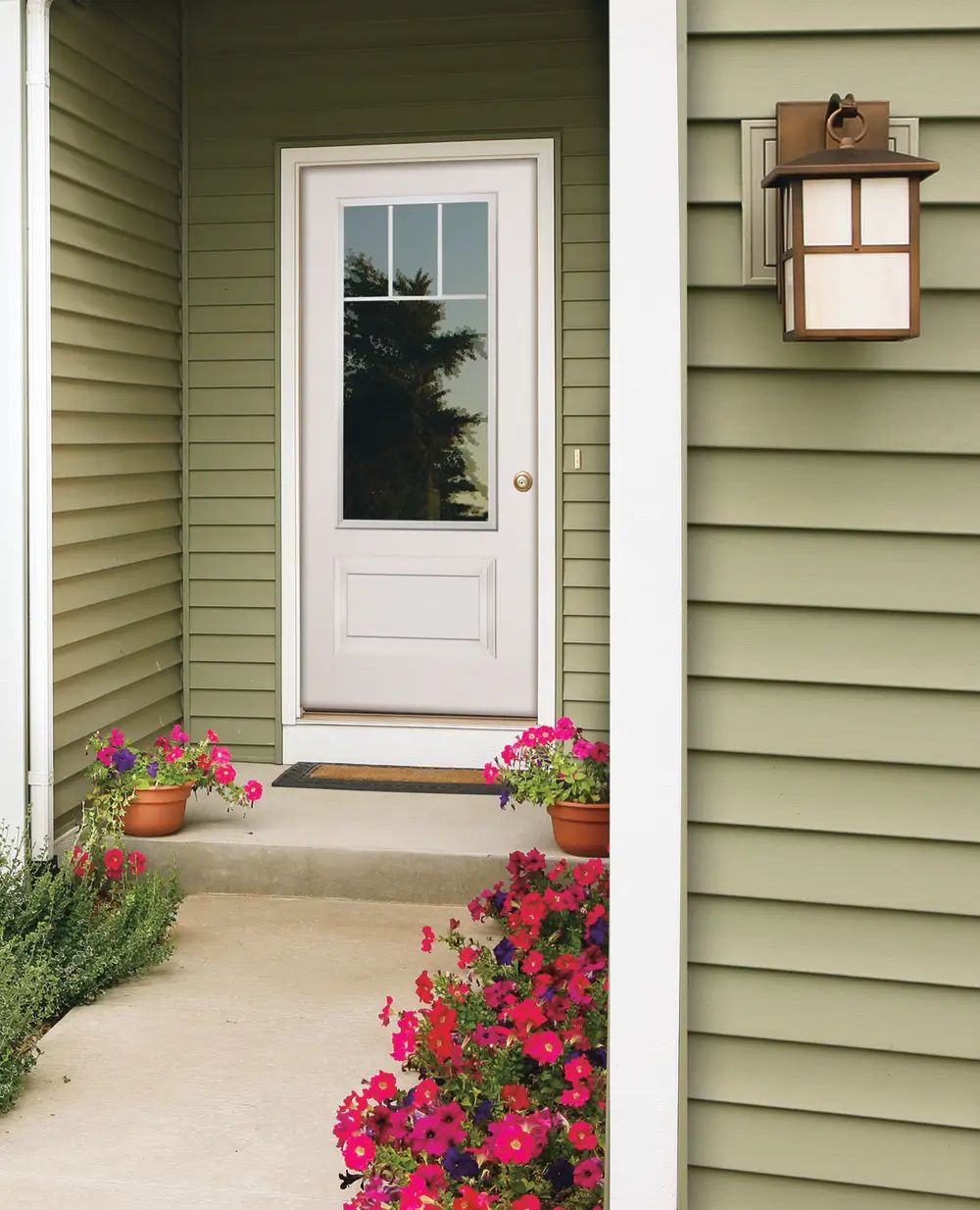 A charming front Door surrounded by vibrant flowers and illuminated by a porch light, enhancing its inviting appeal.