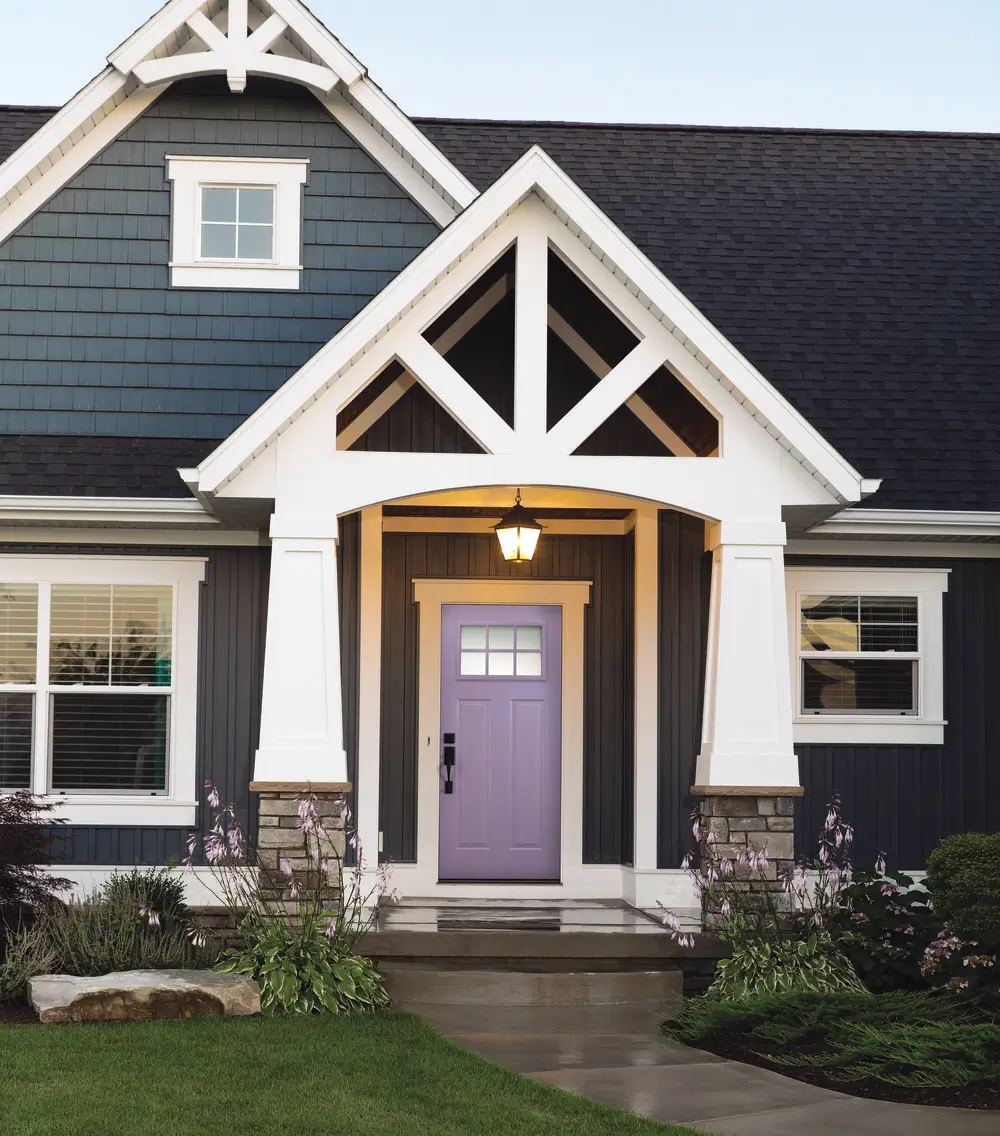A house displaying a bold purple Door framed by white trim, creating a visually appealing and welcoming facade.