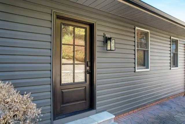Gray house with a black door and window, highlighting a Provia entry door made of steel and fiberglass materials.
