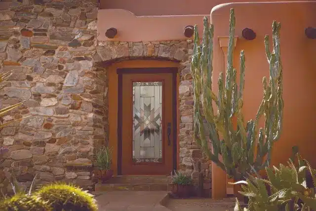 A steel and fiberglass Polaris entry door framed by stone walls and surrounded by cactus plants.