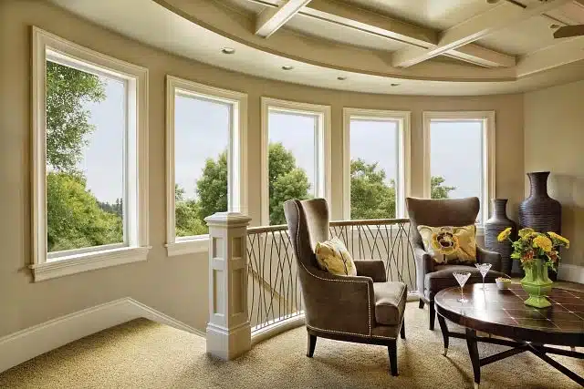 Luxurious seating nook with curved wall, tall white-framed windows, velvet chairs, and a coffered ceiling.
